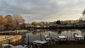 A lakeside restaurant with outdoor seating, a fence, and a view of the town across the water. - Steam Packet Inn (Totnes)