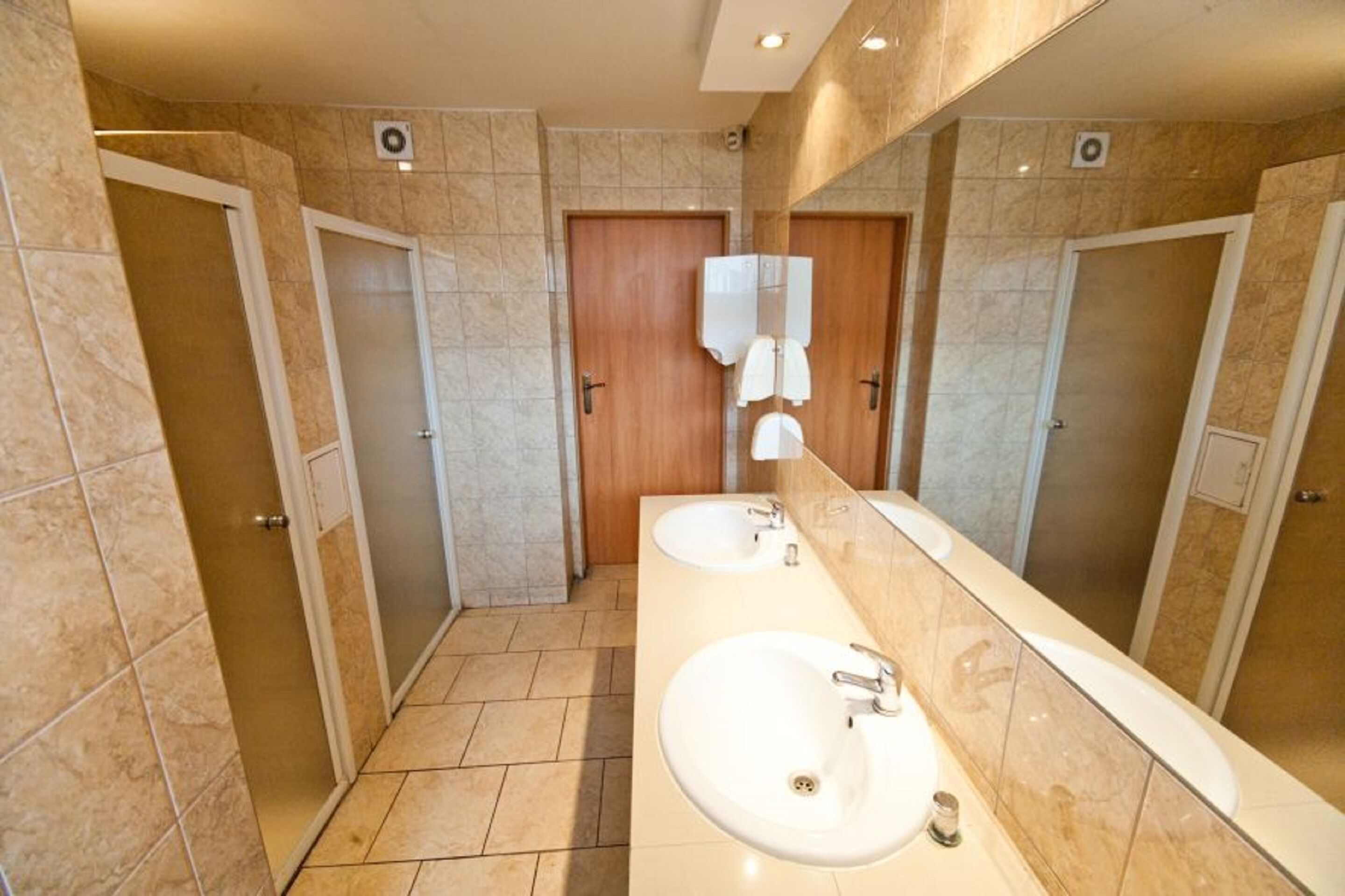 A modern bathroom with two sinks, a large mirror, and a shower area.