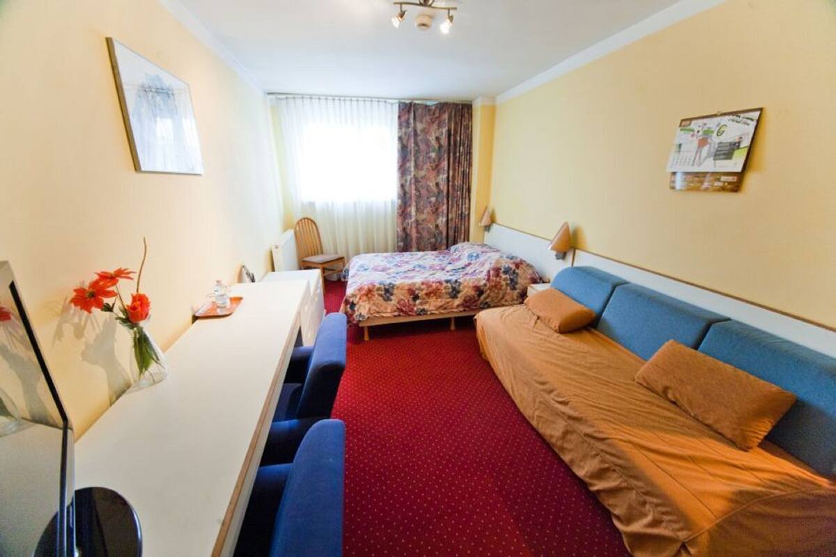 Habitación de hotel con cama, sofá, escritorio y silla.