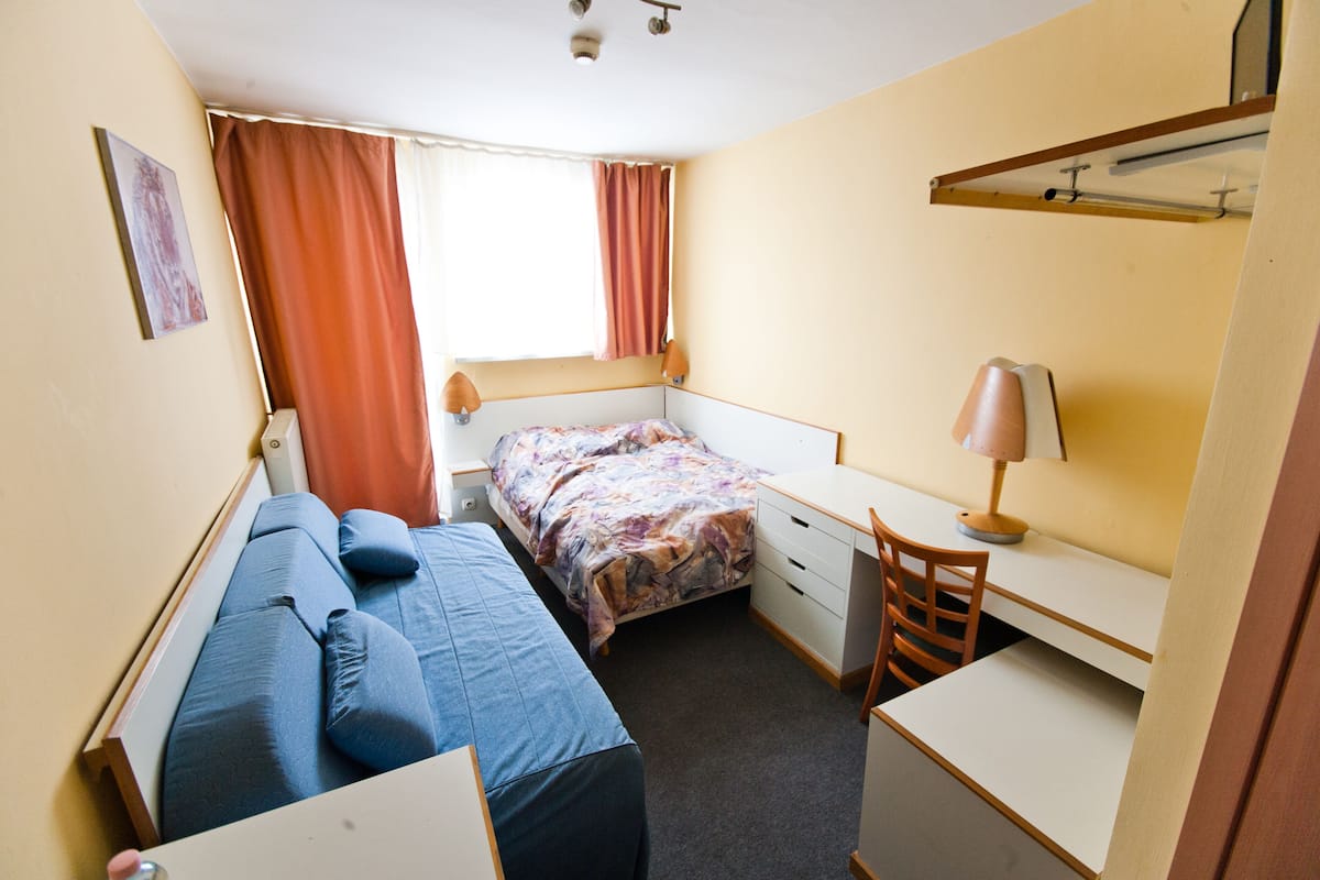 Un dormitorio pequeño con cama, escritorio y silla.