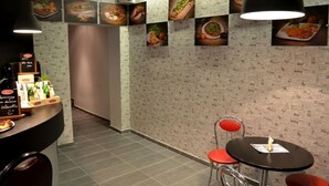 Een restaurantinterieur met een balie, stoelen en een muur versierd met afbeeldingen van eten.