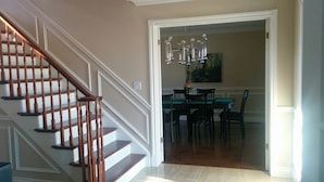 A staircase with wooden balusters leading to a dining area with a chandelier.