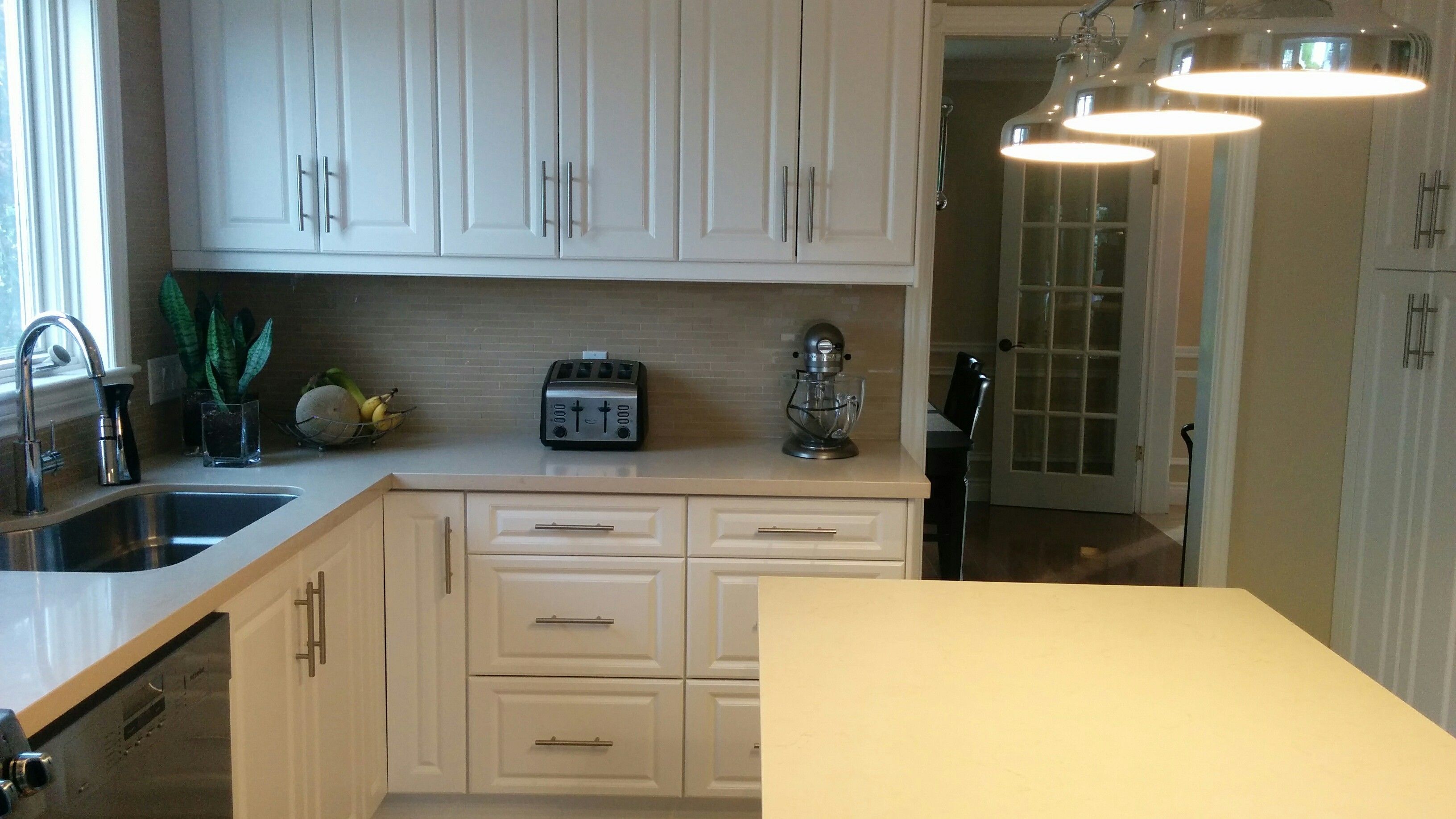 A kitchen with white cabinets, a toaster, a mixer, and a sink.
