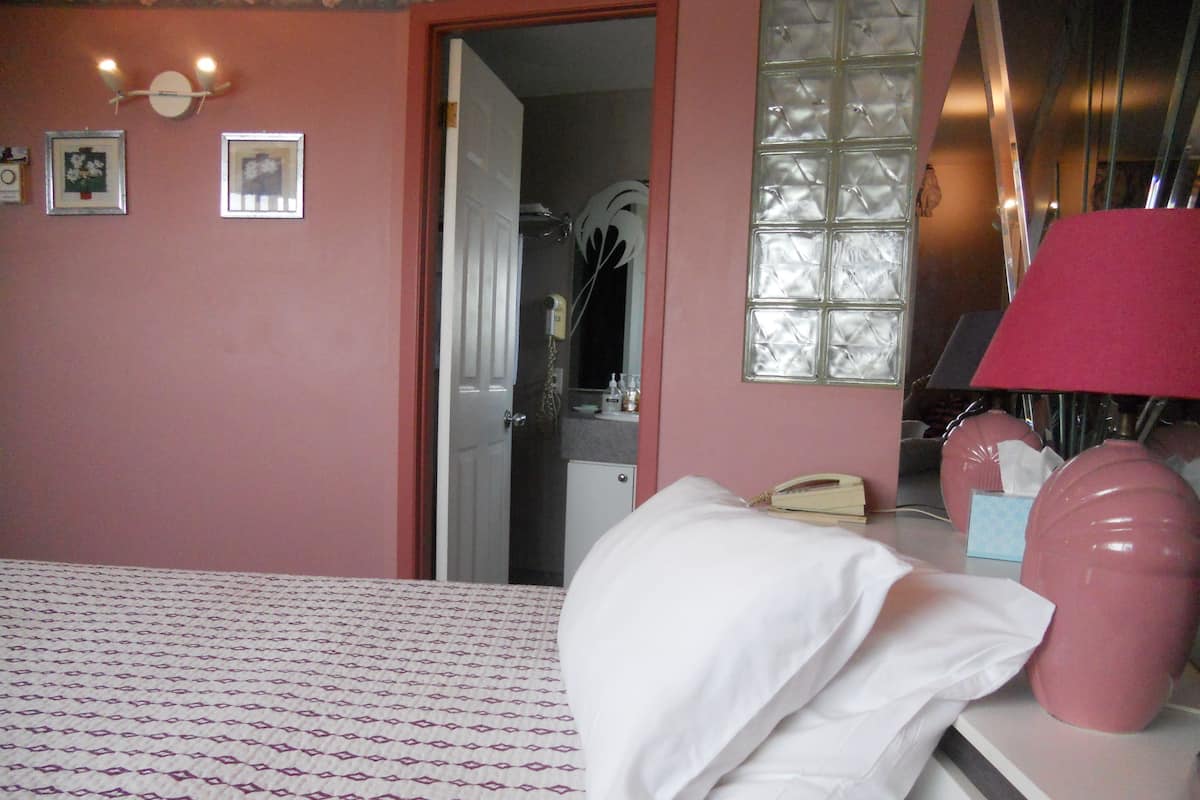 Una habitación de hotel con cama, escritorio, teléfono y espejo.