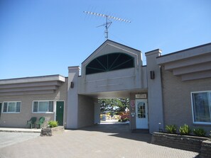 Un bâtiment doté d’une entrée centrale, d’un toit plat et d’une antenne visible.