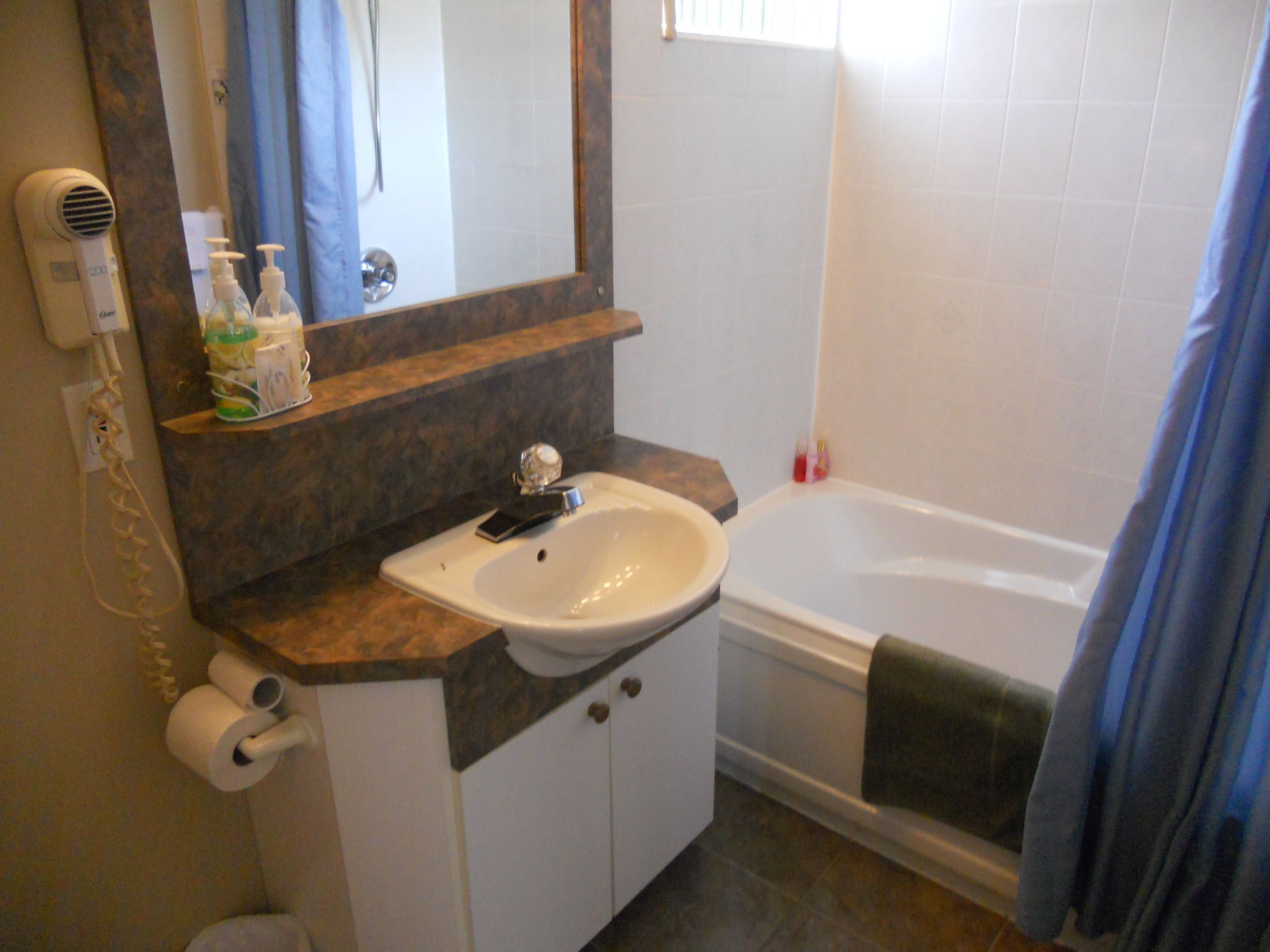 A bathroom with a sink, mirror, and bathtub.