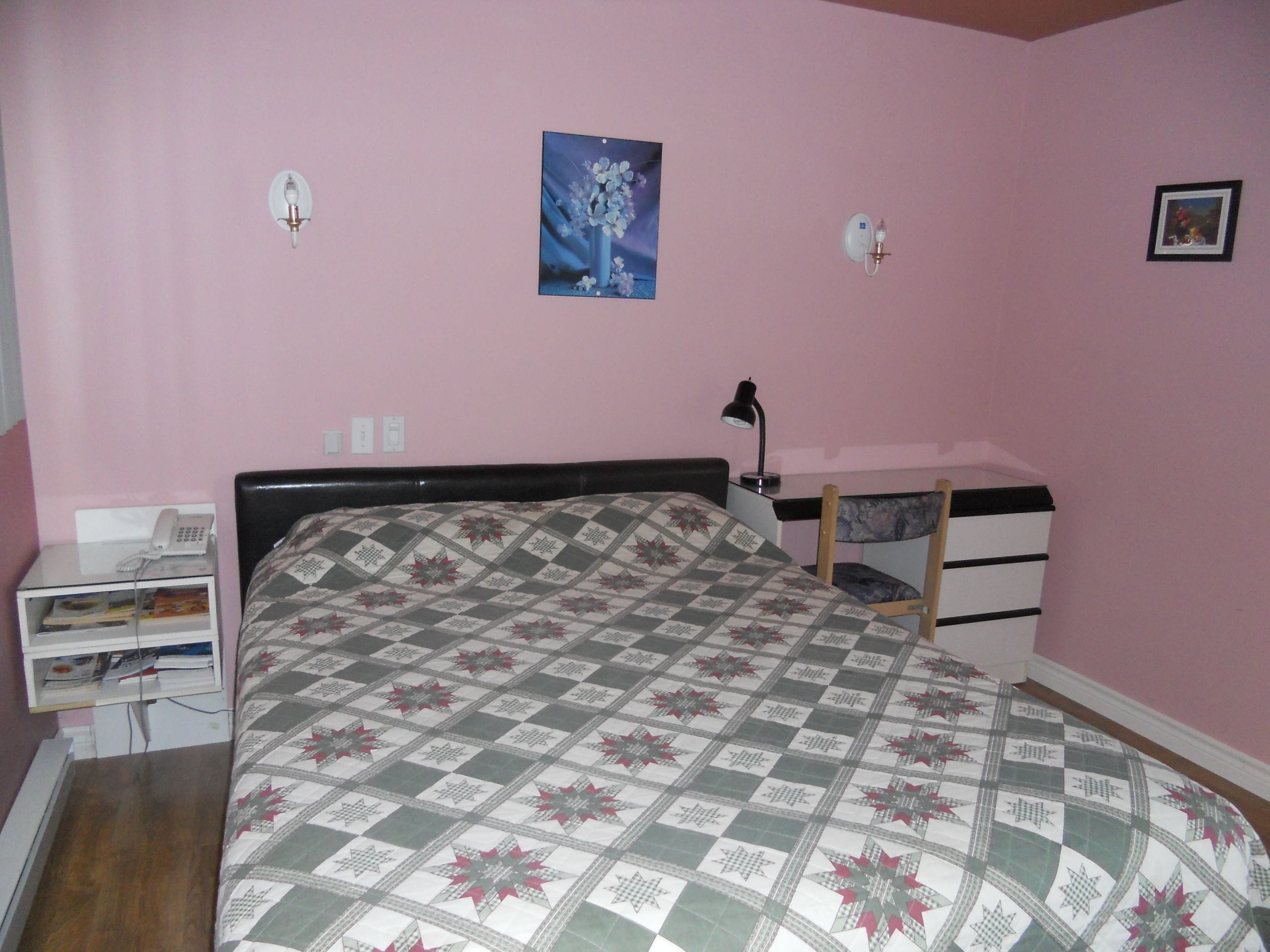 Un dormitorio con cama, escritorio, silla y mesita de noche.