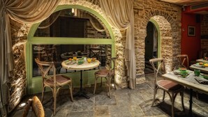 Un comedor rústico con paredes de piedra, sillas de madera y una mesa lista para dos comensales.