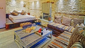 Una habitación acogedora con pared de piedra, cama, sofá, mesa de centro y chimenea.