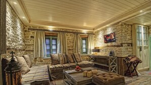 Una habitación acogedora con paredes de piedra, un sofá de madera, una mesa de centro y un televisor.