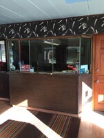 Un mostrador de recepción con un cartel de 'No Fumar', una vitrina de cristal y una puerta de madera.
