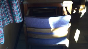 Une pièce avec une table en bois, une chaise, une lampe et un rideau à motifs.