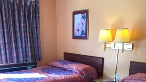 Une chambre d’hôtel avec deux lits, une table de chevet, une lampe et un tableau encadré au mur.