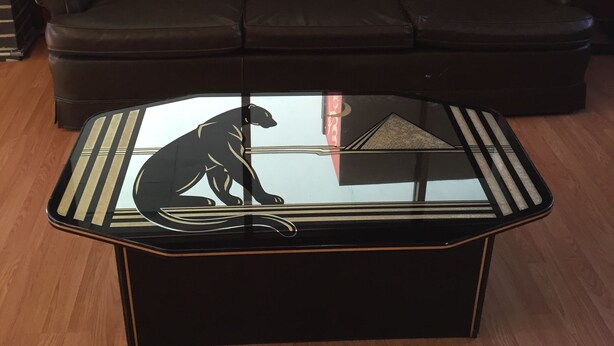 Un canapé en cuir marron et une table basse en verre ornée d’un motif de panthère noire.