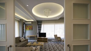 Una sala de estar moderna con sofá, mesa de centro, televisor y candelabro.