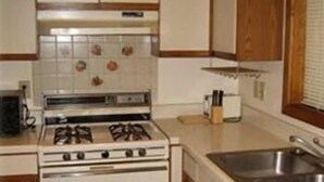 A kitchen with white cabinets, a stove, and a sink. - Chapel Hill InnTown (Chapel Hill)