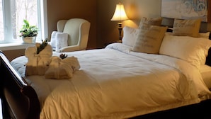 A neatly made bed with white linens, a lamp, a chair, and a painting on the wall. - L'Oasis de l'Île, Refuge Urbain (Saint-Eustache)
