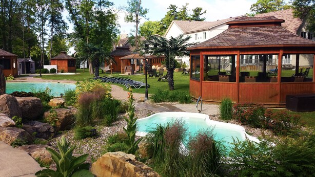 A resort with multiple swimming pools, wooden cabins, and a covered seating area. - L'Oasis de l'Île, Refuge Urbain (Saint-Eustache)