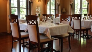 A dining area with tables set for six, wooden chairs, and a white tablecloth. - L'Oasis de l'Île, Refuge Urbain (Saint-Eustache)