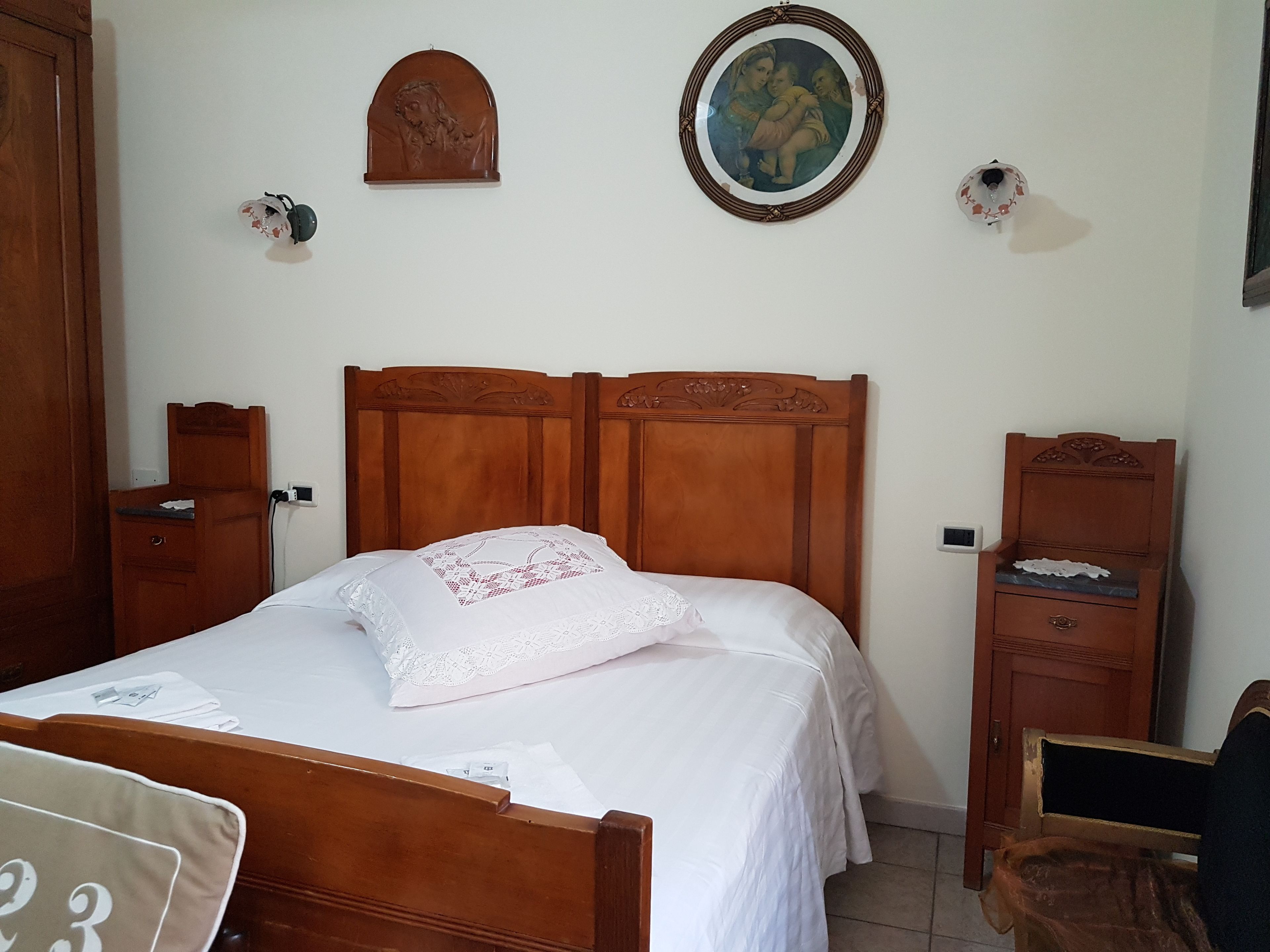 Quarto com cama de madeira, mesa de cabeceira, cômoda e um quadro na parede.
