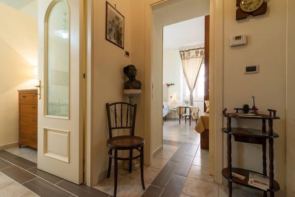 A hallway with a wooden chair, a small table, and a shelf with books. - Da Agnese Locazioni brevi (Cagliari)