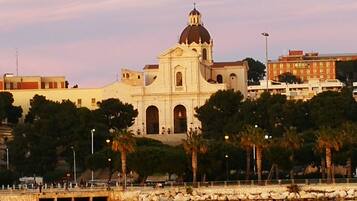 Un edificio grande de color blanco con una cúpula y ventanas arqueadas, rodeado de árboles y una orilla de agua.