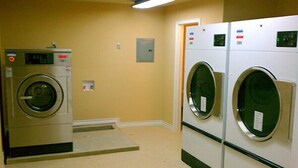 Una sala de bugaderia amb dues rentadores de càrrega frontal i una assecadora.