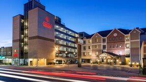 A hotel with a modern building featuring a prominent sign, a covered entrance, and a parking area. - Aspen Select (Rochester)