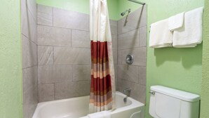 A bathroom with a bathtub, shower curtain, and a toilet. - Budget Inn Jennings LA I-10 (Jennings)