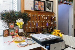 Un escritorio con iconos religiosos, plumas de pavo real y una calculadora.