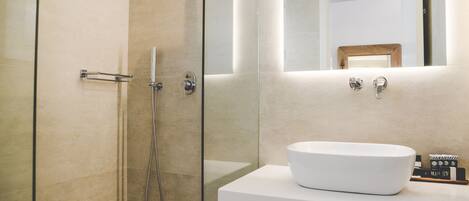 Une salle de bain moderne avec une douche à parois de verre, un lavabo blanc et un miroir au-dessus du lavabo.