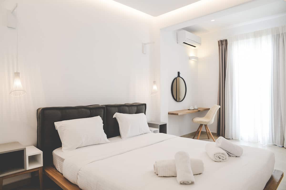 A modern hotel room with a large bed, a desk, and a chair.