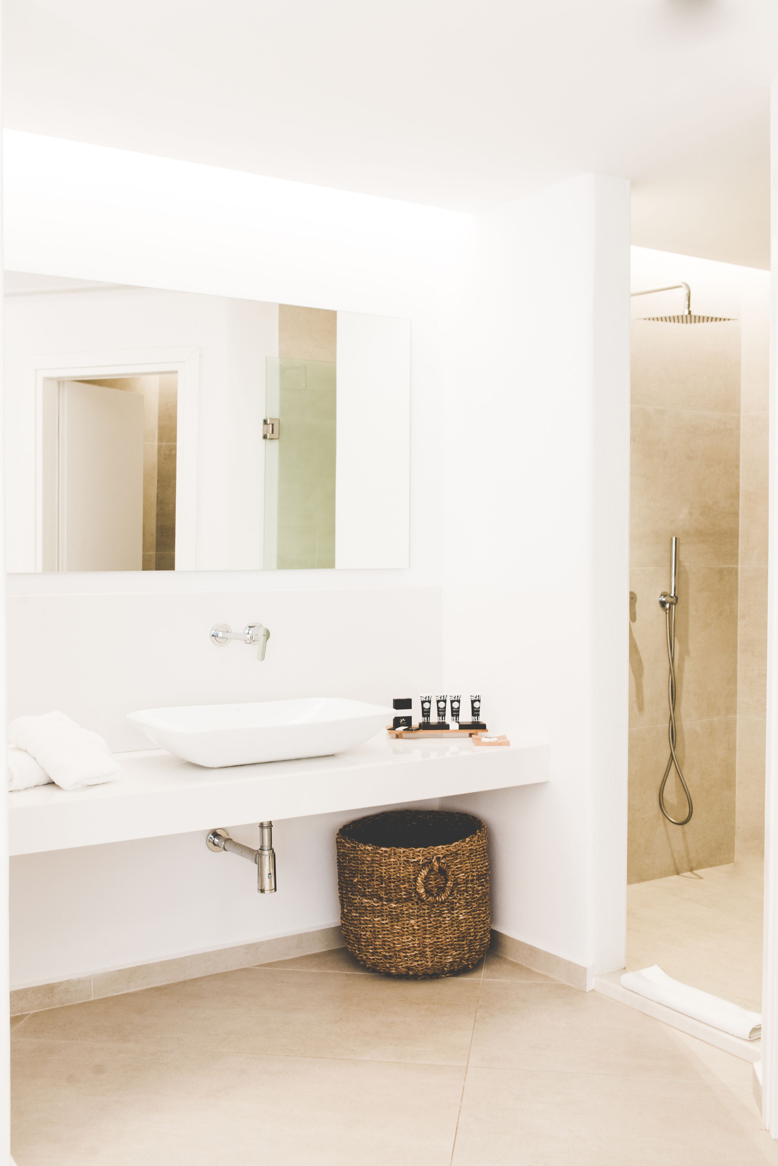 Een moderne badkamer met een wit wastafelmeubel, spiegel en douche.
