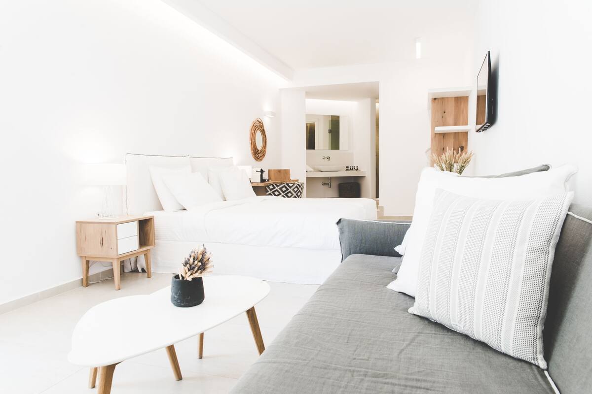 Un dormitorio moderno y luminoso con cama, mesita de noche y un pequeño escritorio con espejo.