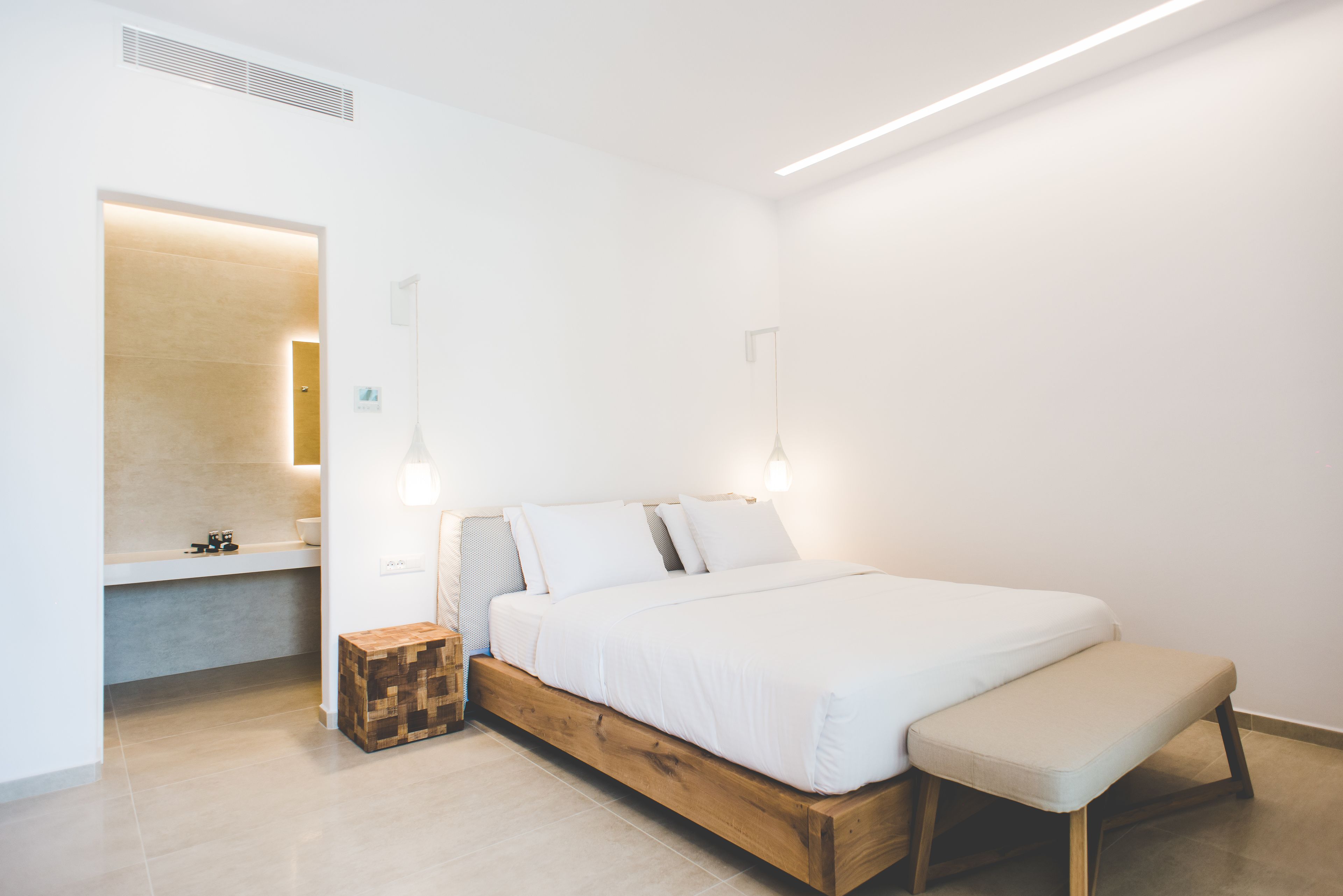 Une chambre à coucher moderne avec un cadre de lit en bois, un banc, une table de chevet et un banc intégré au pied du lit.