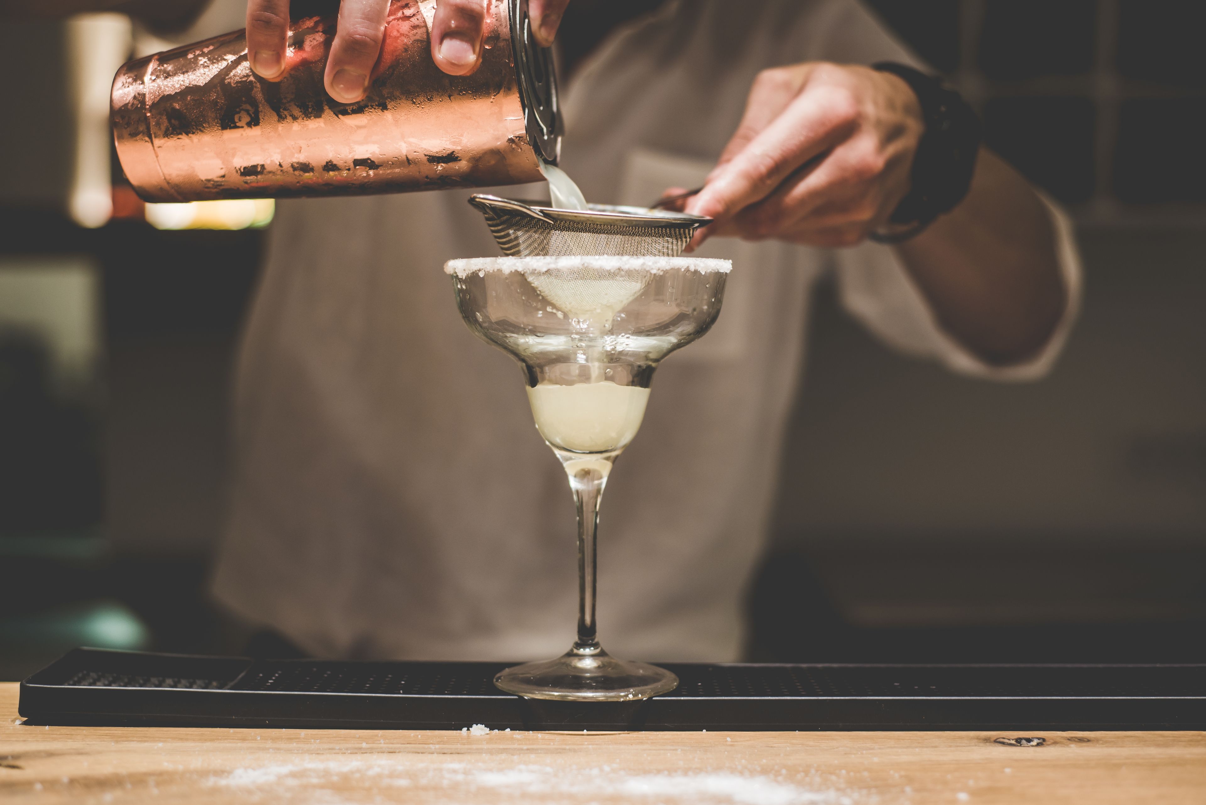 A bartender pouring a drink into a martini glass.