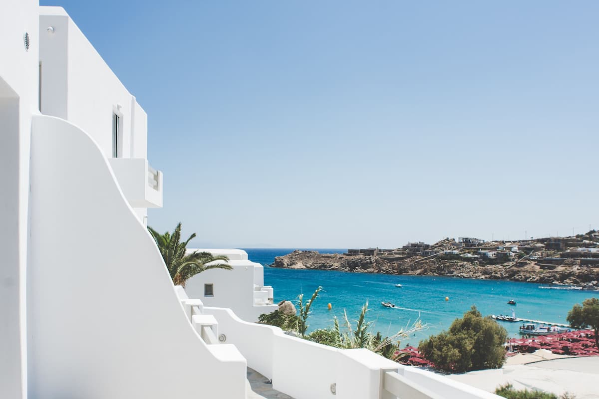 Un edificio blanco con una terraza de madera y vista al mar.