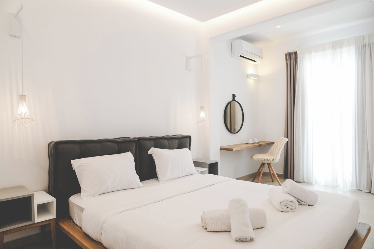 A modern hotel room with a large bed, a desk, and a chair.