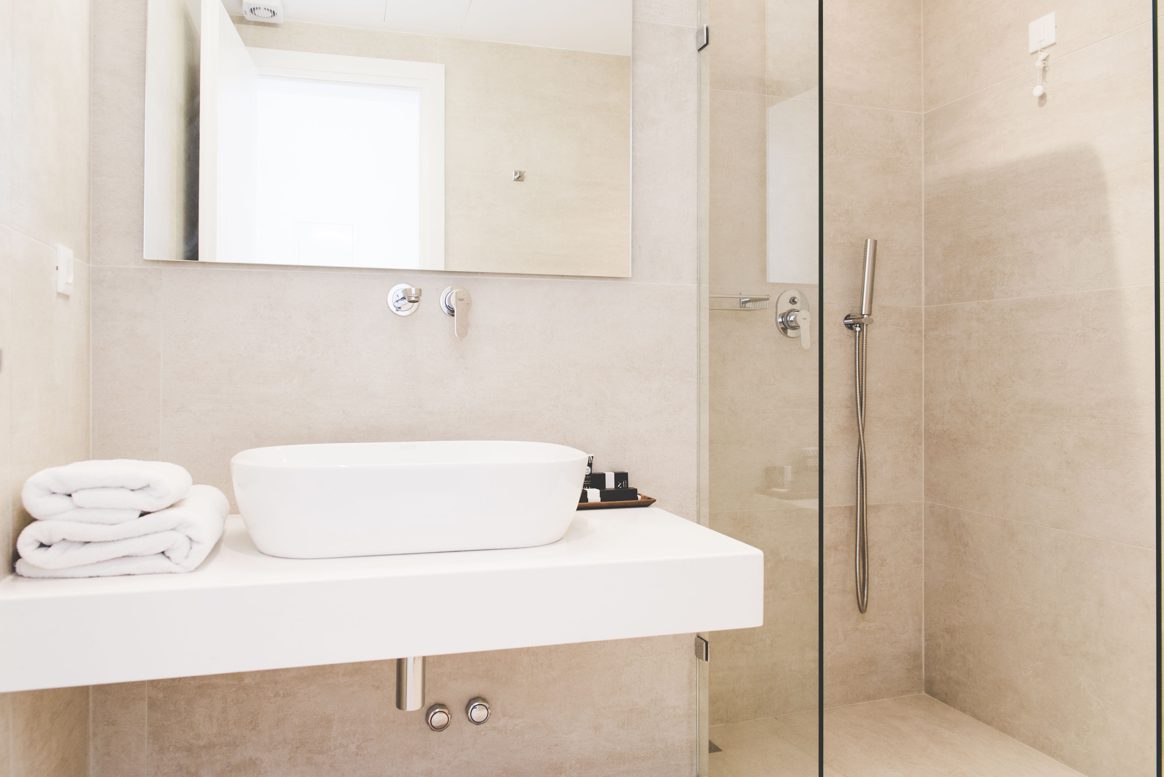 A modern bathroom with a white sink, a mirror above it, and a glass-enclosed shower area.
