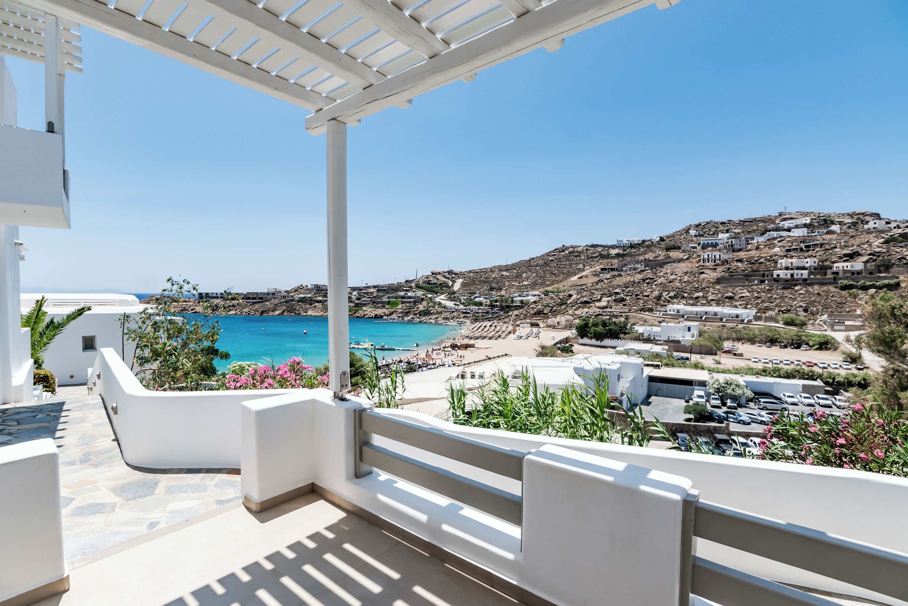 A balcony with a view of a coastal town, a beach, and a clear blue sea.