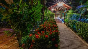 A pathway leading to a covered structure surrounded by lush greenery and flowering plants. - Hotel South Beach (Jacó)