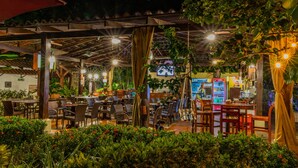 An outdoor dining area with tables and chairs, a covered seating area, and a vending machine. - Hotel South Beach (Jacó)