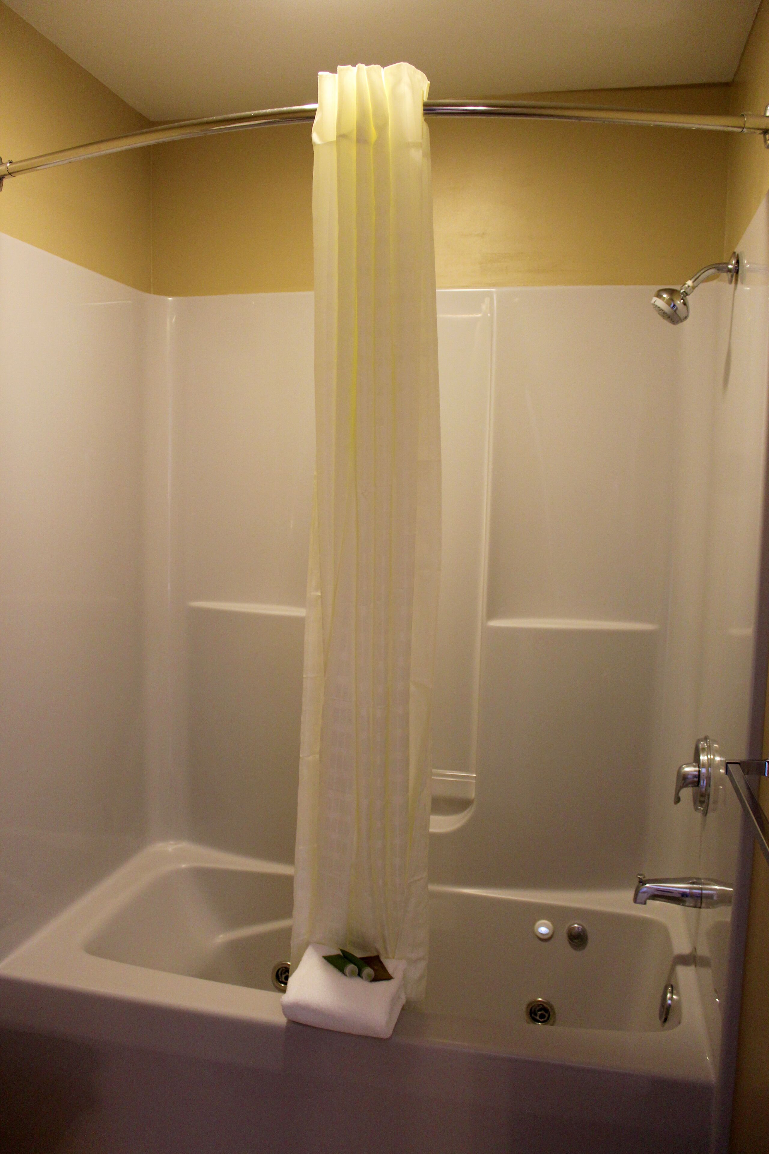 A shower with a curtain, a bathtub, and a showerhead.