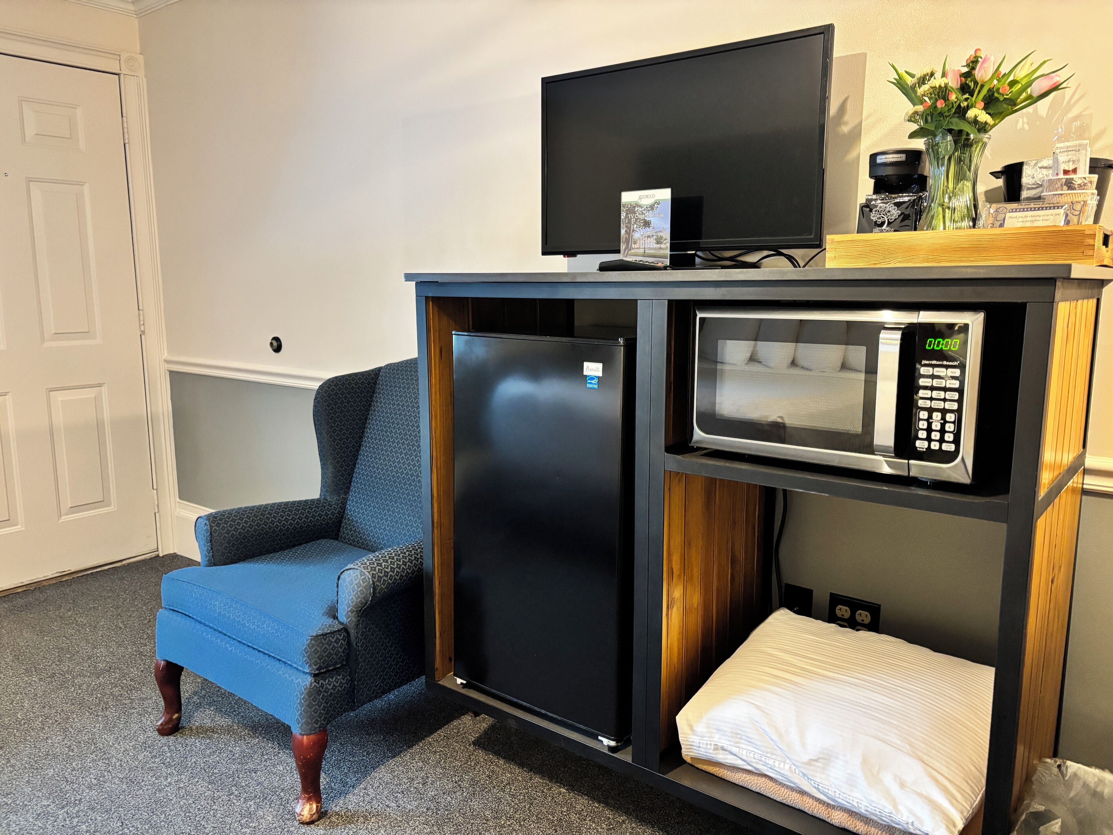 A compact kitchenette with a refrigerator, microwave, and a small TV.