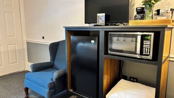 A compact kitchenette with a refrigerator, microwave, and a small TV.