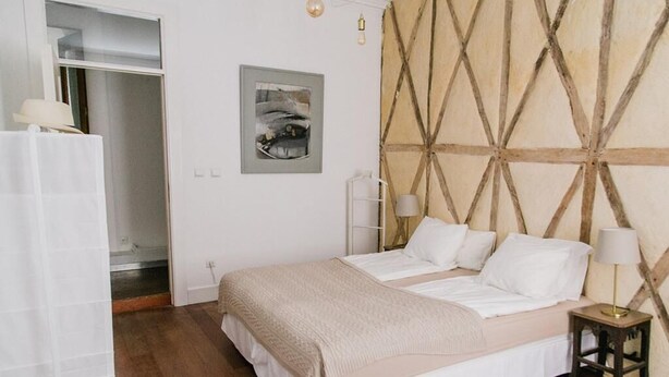 A bedroom with a bed, bedside lamps, a wooden headboard, a framed artwork, and a wooden floor. - Asul B&B (Lisbon)