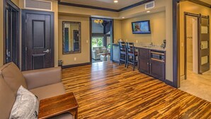 A spacious living area with a wooden floor, a sofa, a coffee table, and a kitchen area with a dining table and chairs. - Berlin Resort (Millersburg)