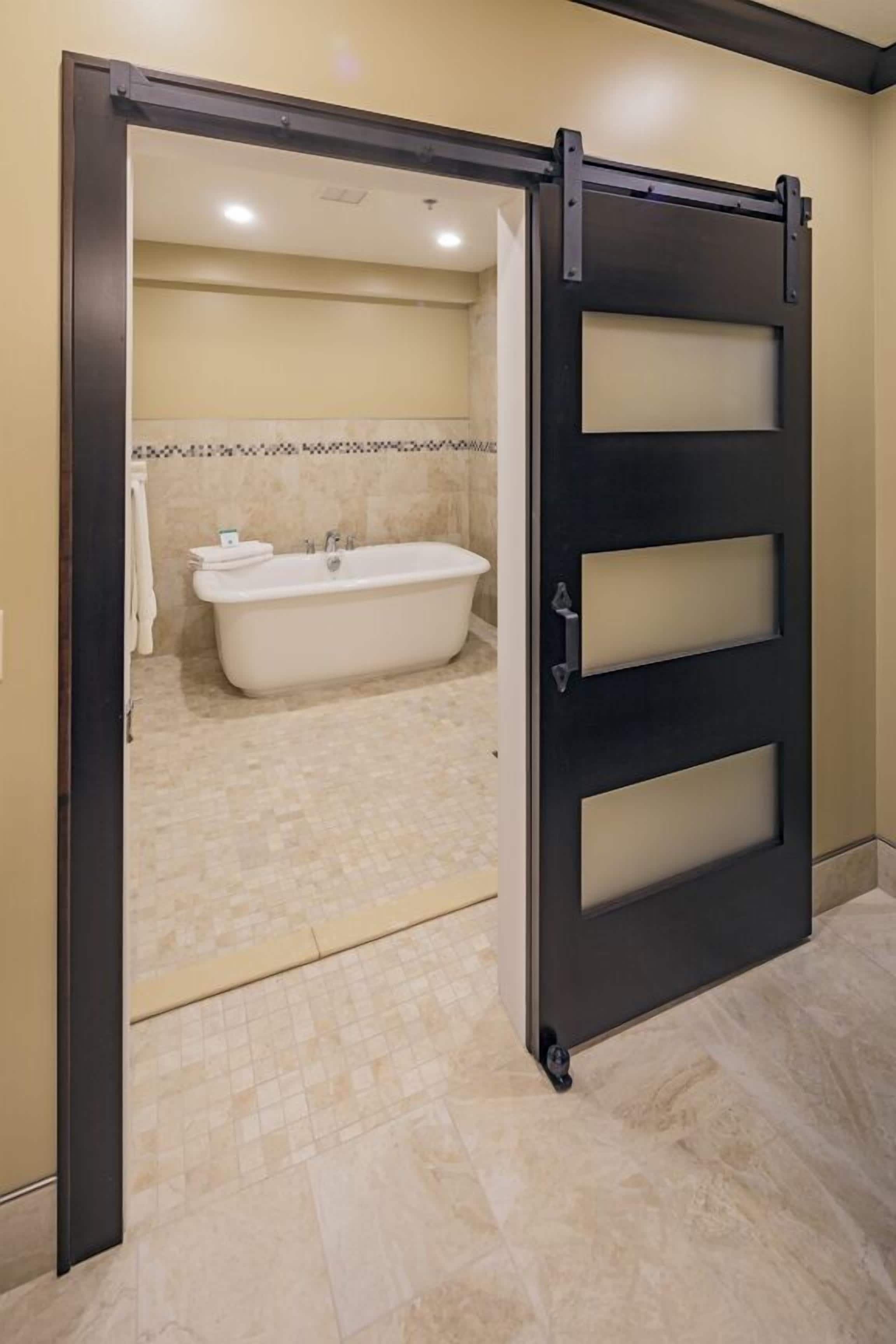 A bathroom with a bathtub, a towel rack, and a sliding door.