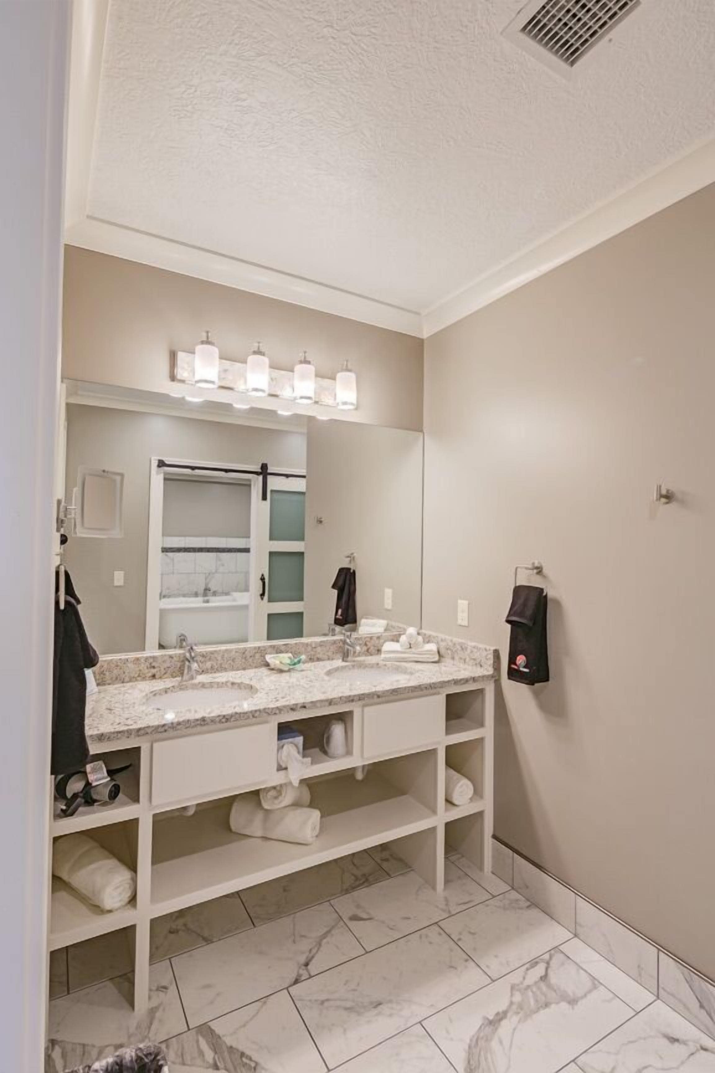 A bathroom with a double sink vanity, a large mirror, and a towel rack.