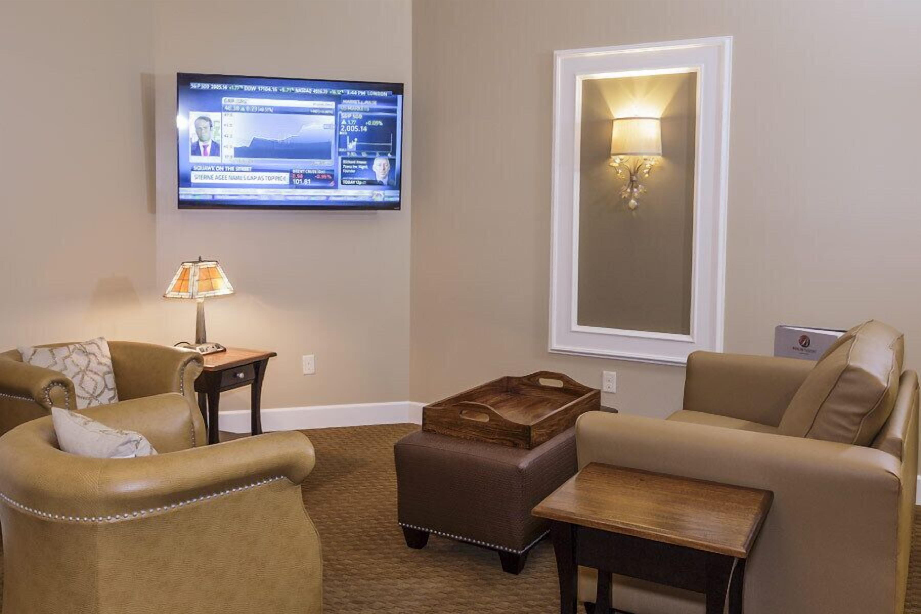 Una sala de estar con dos sofás de cuero, una mesa de centro de madera, una lámpara y un televisor montado en la pared.
